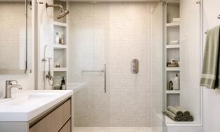 After renovation view of a tiled walk-in shower bathroom with brushed fixtures