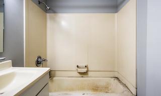 Before renovation view of a dated bathroom with a built-in bathtub